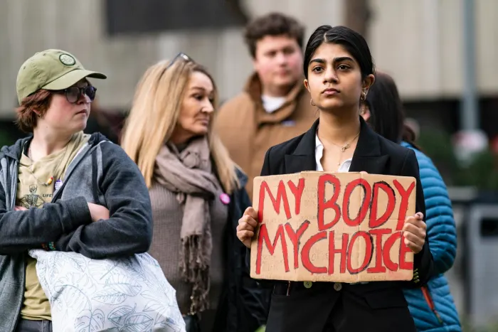 Woman holding sign at rally saying 